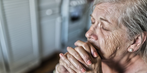 older woman praying by herself